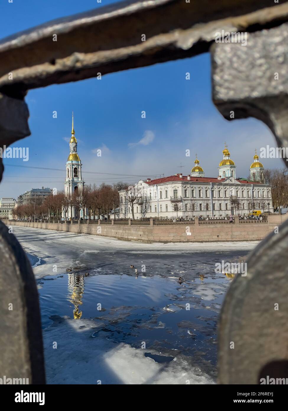 Russland, St.Petersburg, 02. April 2021: Der Glockenturm der St. Nikolaus-Marinekathedrale durch das geschmiedete Gitter an einem klaren, sonnigen Frühlingstag, einer Eisdrift Stockfoto