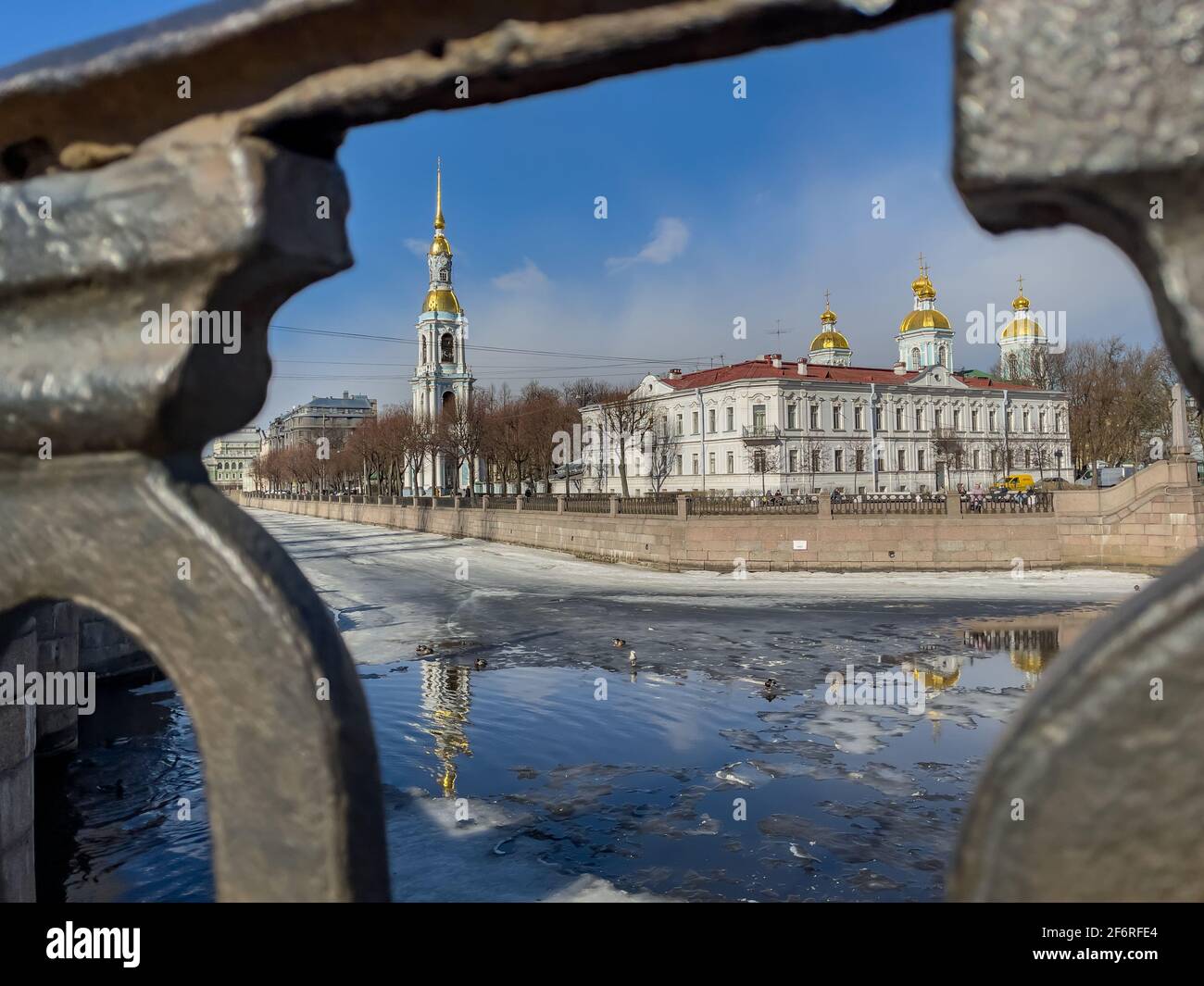 Russland, St.Petersburg, 02. April 2021: Der Glockenturm der St. Nikolaus-Marinekathedrale durch das geschmiedete Gitter an einem klaren, sonnigen Frühlingstag, einer Eisdrift Stockfoto