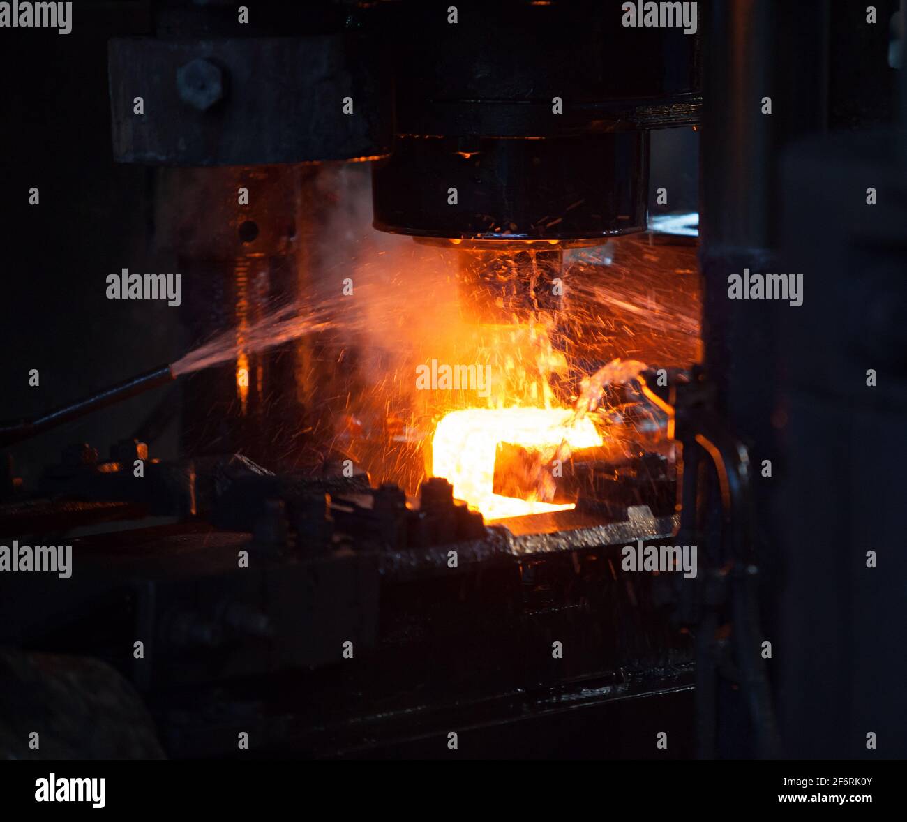 Lageranlage. Stanzen des Innenrings des Lagers auf einer mechanischen Presse. Wasserkühlung des Metalls.Weißes heißes Metall Stockfoto