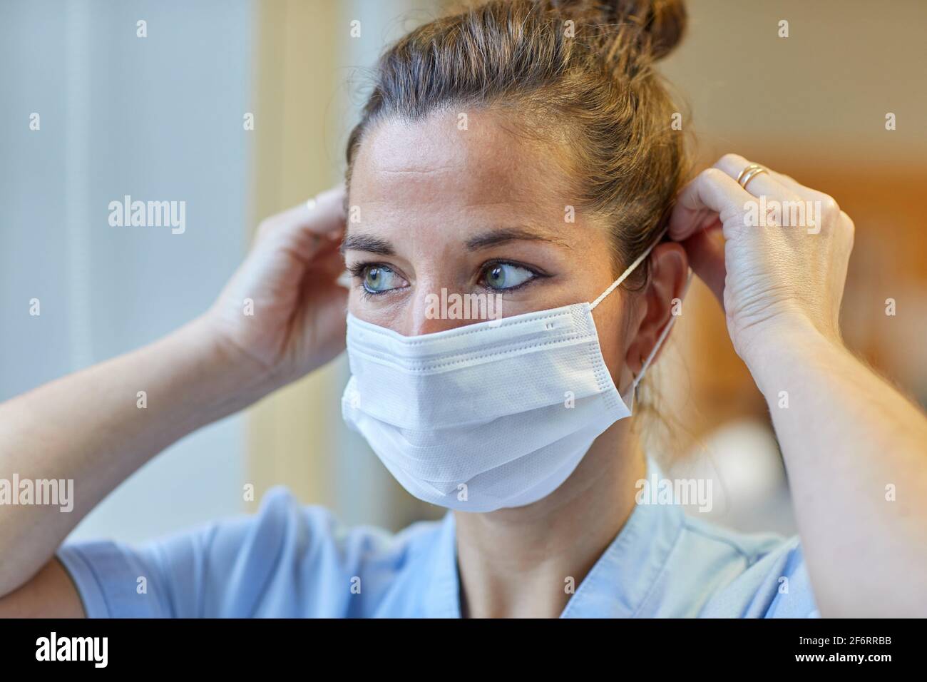 Porträt einer Krankenschwester, die eine Schutzmaske aufsetzt, Krankenschwester, Krankenhaus Stockfoto