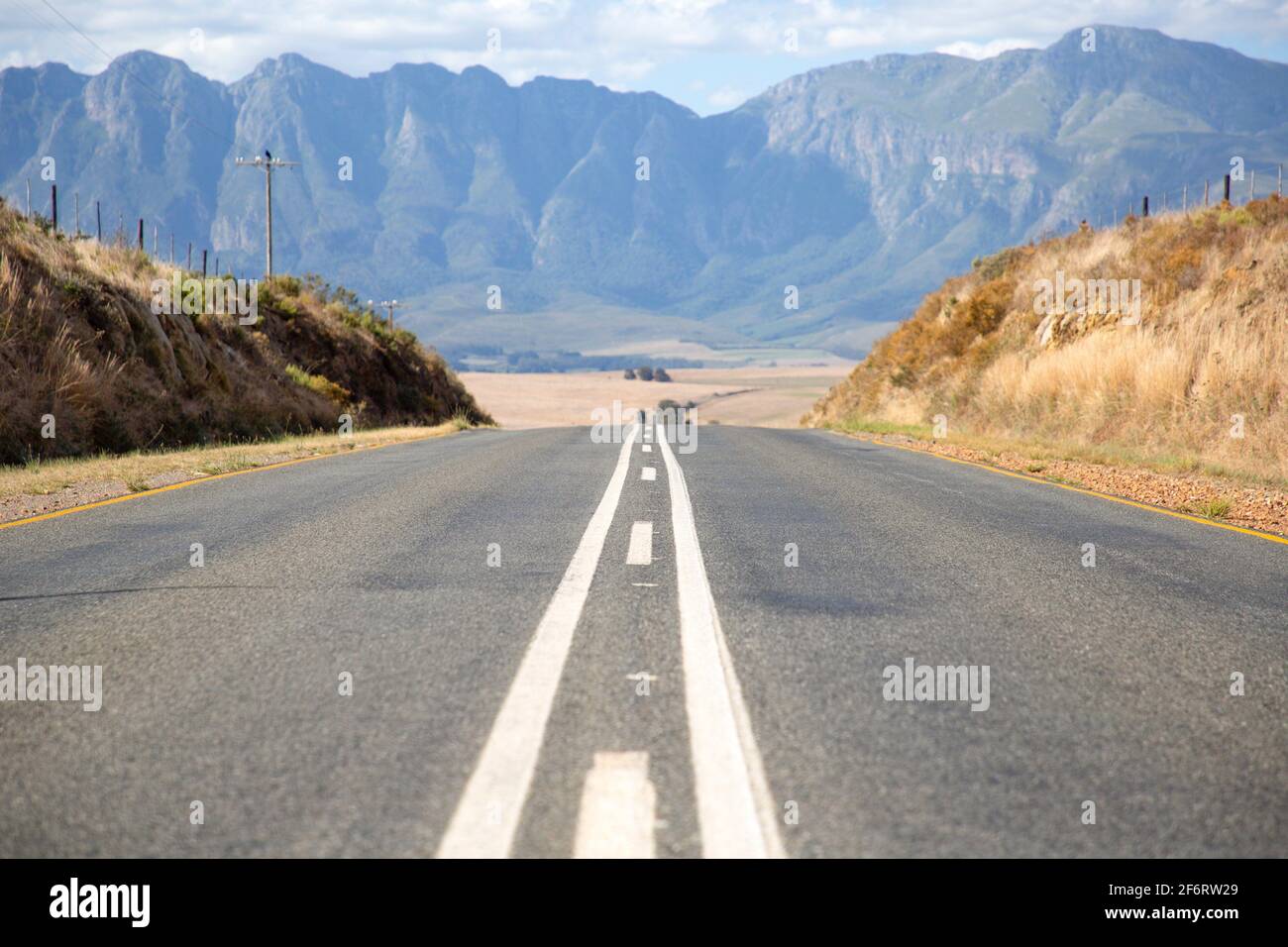 Symmetrie der Straße mit Medianstreifen vor den Bergen in Südafrika. Stockfoto