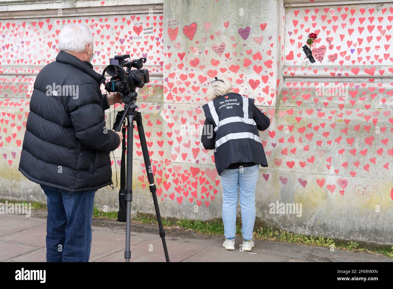 Die Fernsehmediencrew filmt ehrenamtlich, wie sie rotes Herz auf der nationalen Gedenkmauer am Londoner Südufer am Ufer des Uferdamms, England, malte Stockfoto