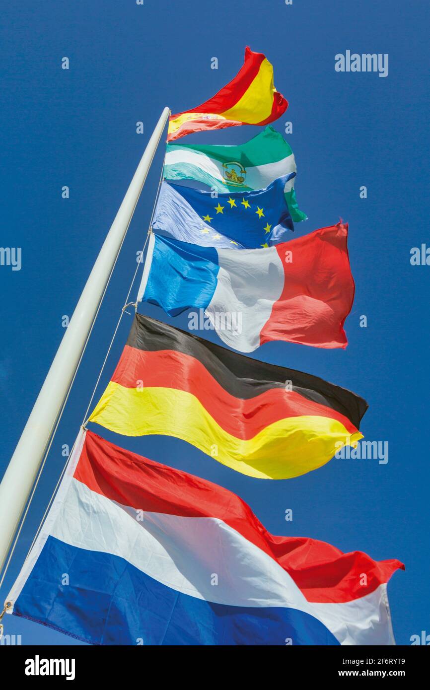 Verschiedene europäische Flaggen fliegen. Von oben: Spanische, andalusische Regionalflagge, Flagge der Europäischen Gemeinschaft, Französisch, Deutsch, Niederlande. Stockfoto