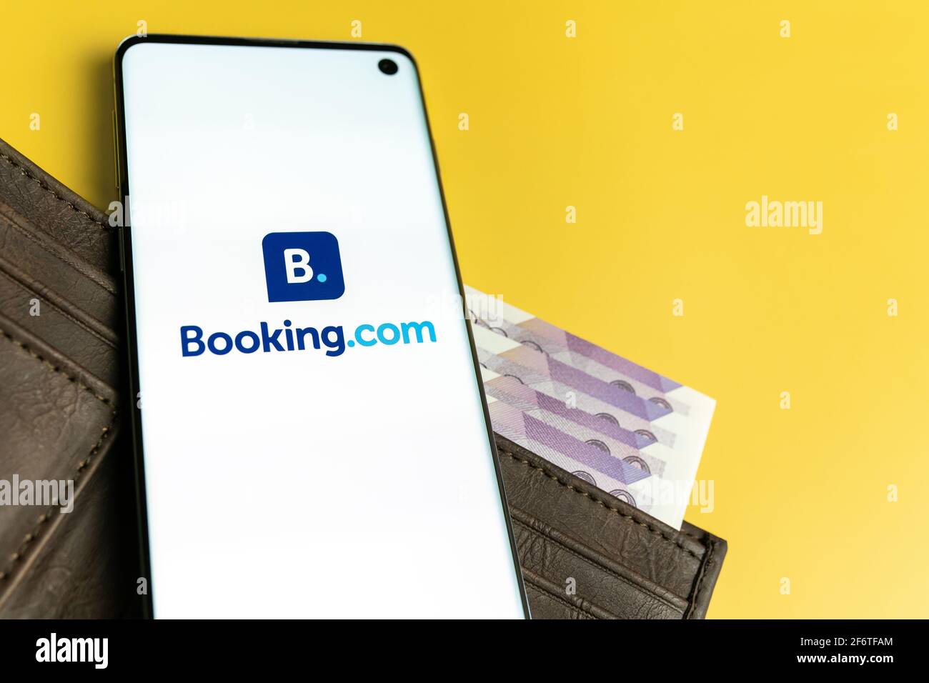 SWANSEA, Großbritannien - 28. MÄRZ 2021: Booking.com App-Logo auf dem Smartphone auf braunem Geldbeutel mit gelbem Hintergrund Stockfoto