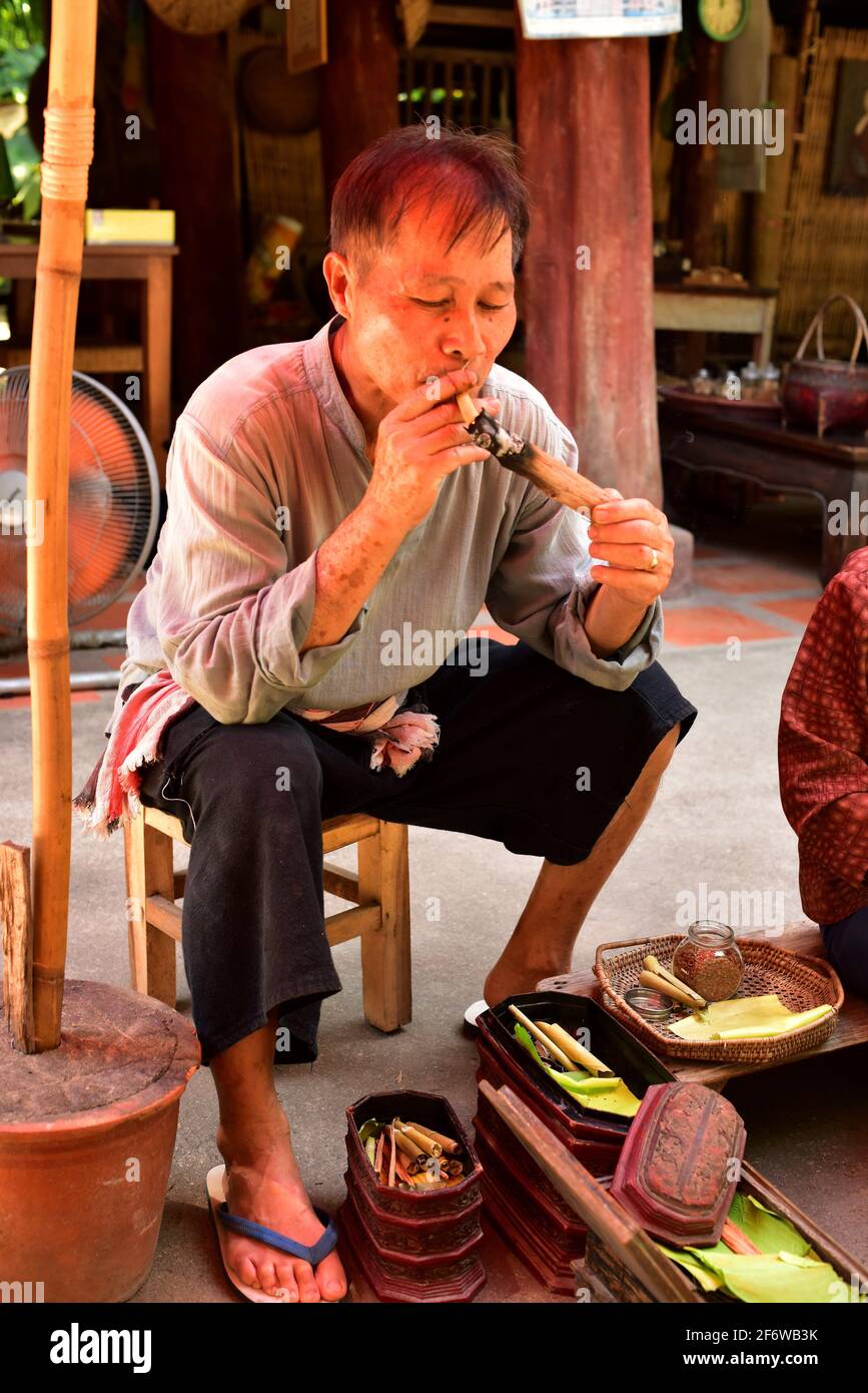 Chiang Mai, Mann, der eine Zigarre auf einem traditionellen Haus raucht. Thailand. Stockfoto