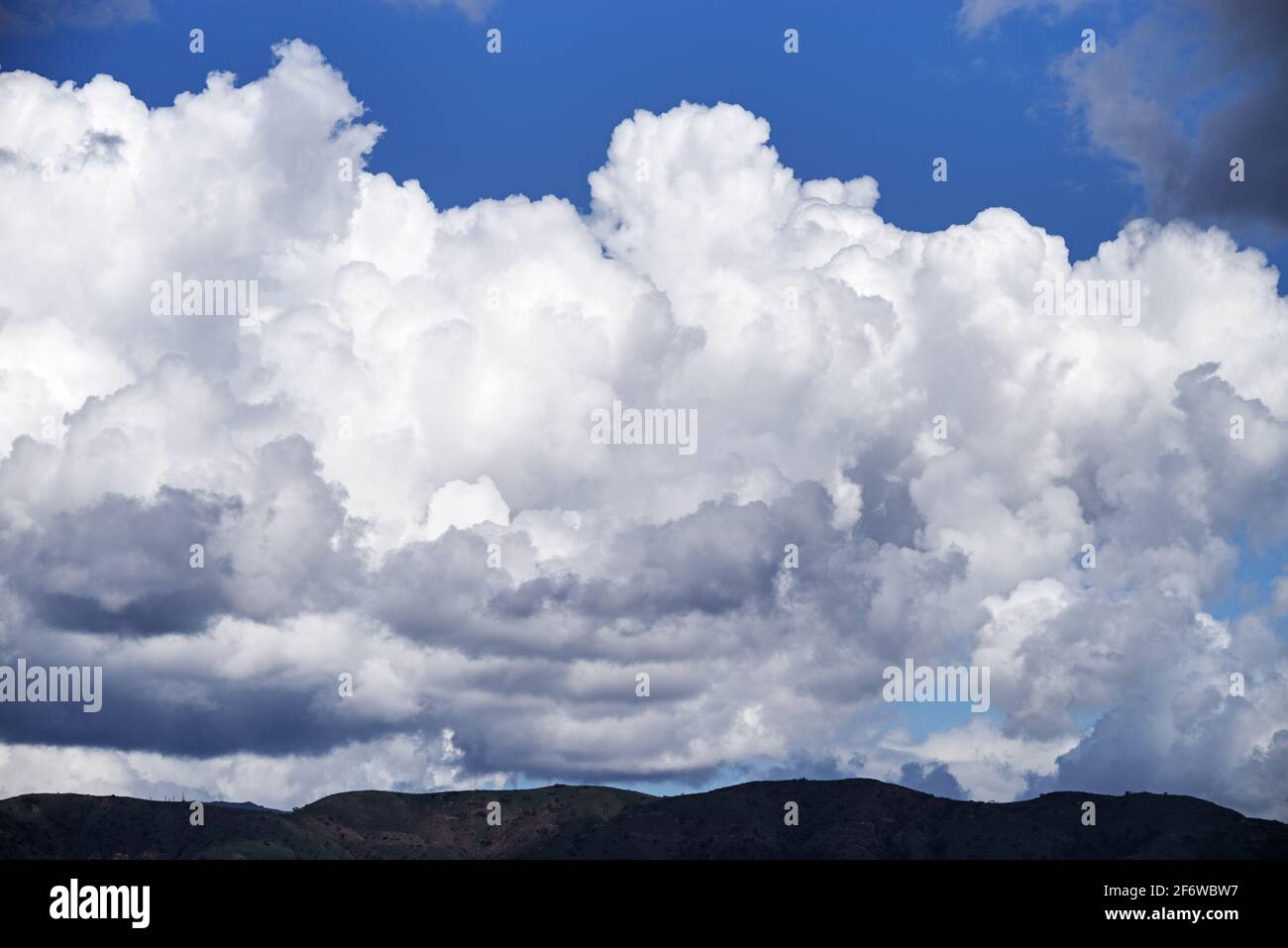 Dramatische Wolken über fernen dunklen Hügeln Stockfoto