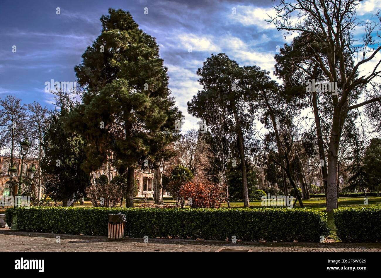 Teil des Wintergartens mit alten hohen Bäumen eingezäunt Mit Buchsbaumsträuchern auf dem Gebiet des Golestan-Palastes In Teheran Stockfoto