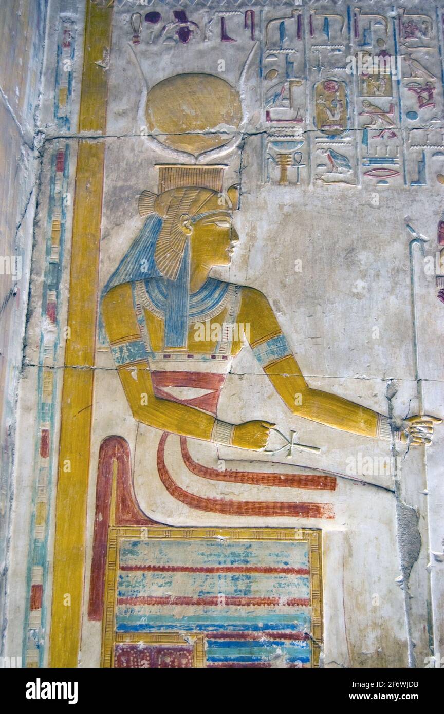 Die altägyptische Göttin Isis saß auf einem Thron und hielt ihr Zepter und das heilige ankh. Bemalte Hieroglyphen-Schnitzerei in einer Innenwand am Tem Stockfoto