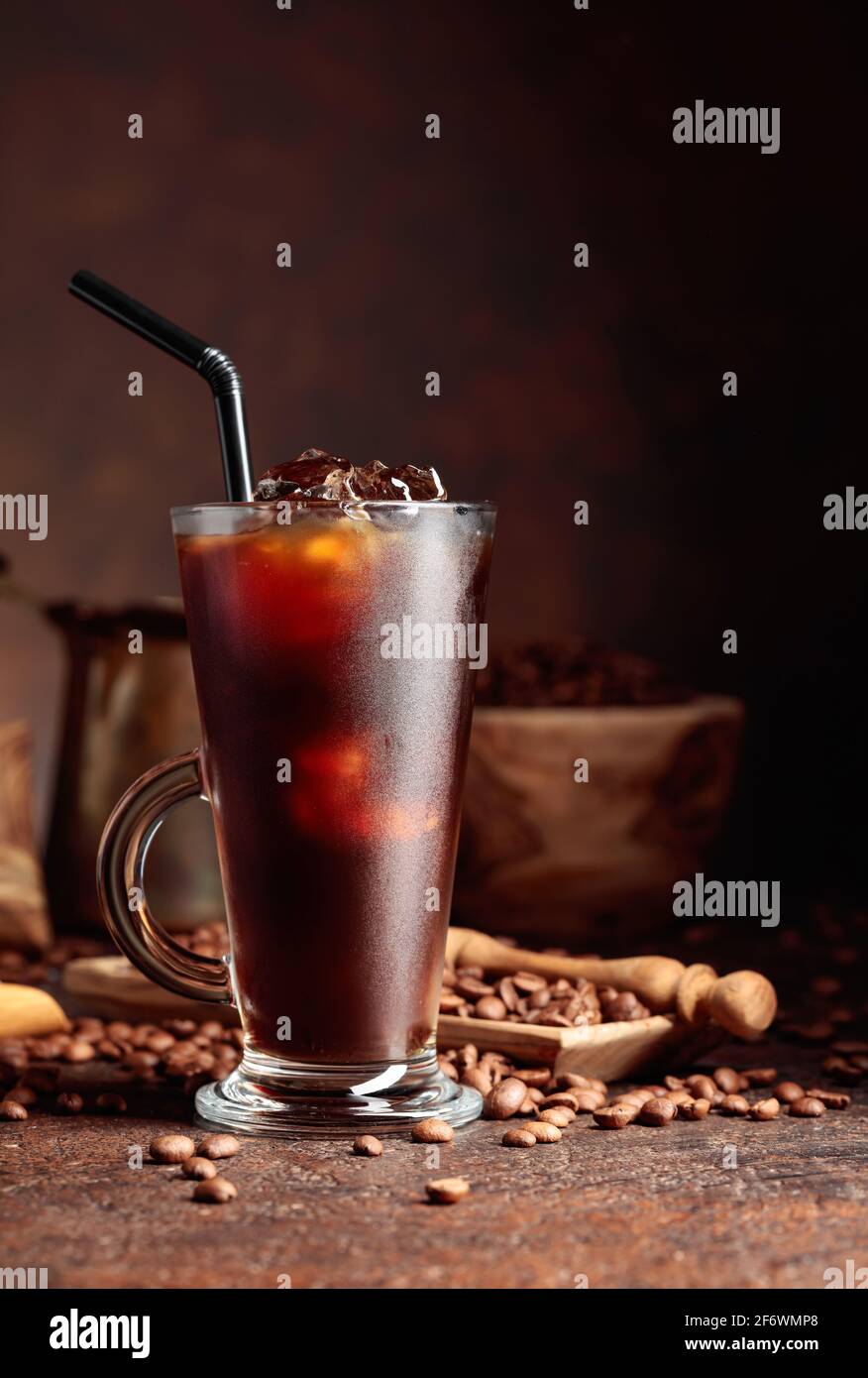 Eiskaffee in gefrorenem Glas und Kaffeebohnen auf einem alten braunen Tisch mit Küchenutensilien. Stockfoto