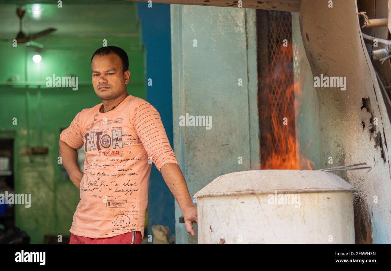 K.R.Market, Bangalore, Indien - Februar 06,2021: Junger Mann steht neben dem Feuer in einer eisernen Kiste Stockfoto