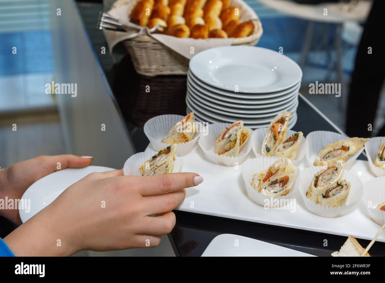 Ein Mann nimmt gefüllte Pfannkuchen auf einer Platte in Pappbechern. Festliche Tischeinstellung. Stockfoto