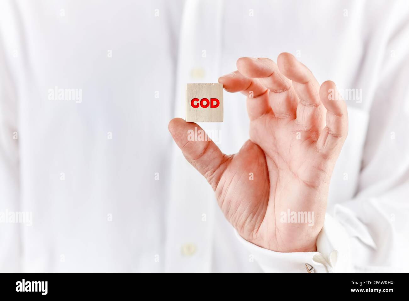 Männliche Hand hält einen Holzwürfel mit dem Wort gott. Religion und Gottesdienst Konzept. Stockfoto