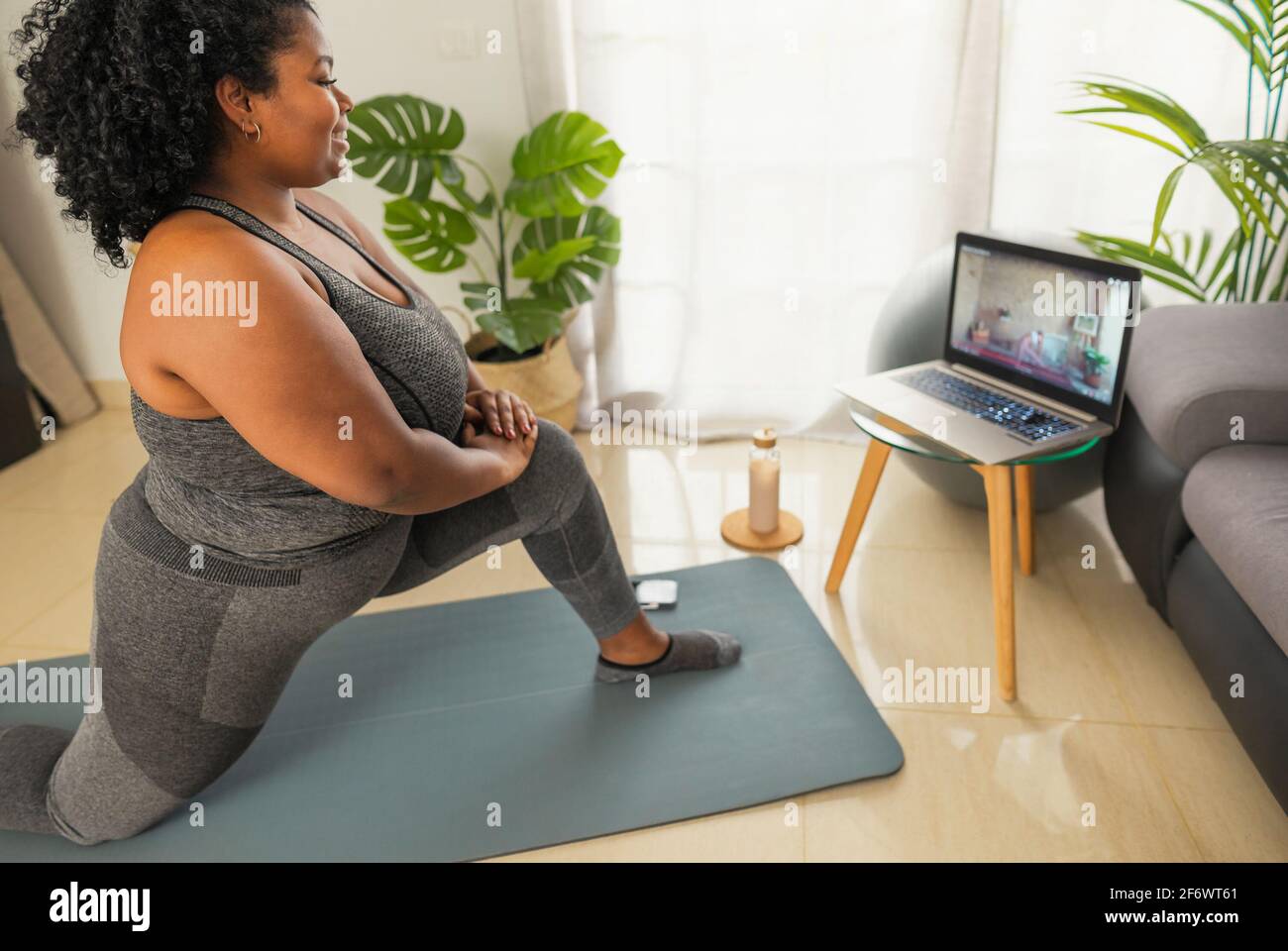 Junge afrikanische Frau macht Pilates virtuellen Fitness-Kurs mit Laptop Zu Hause - Sport Wellness People Lifestyle Konzept Stockfoto