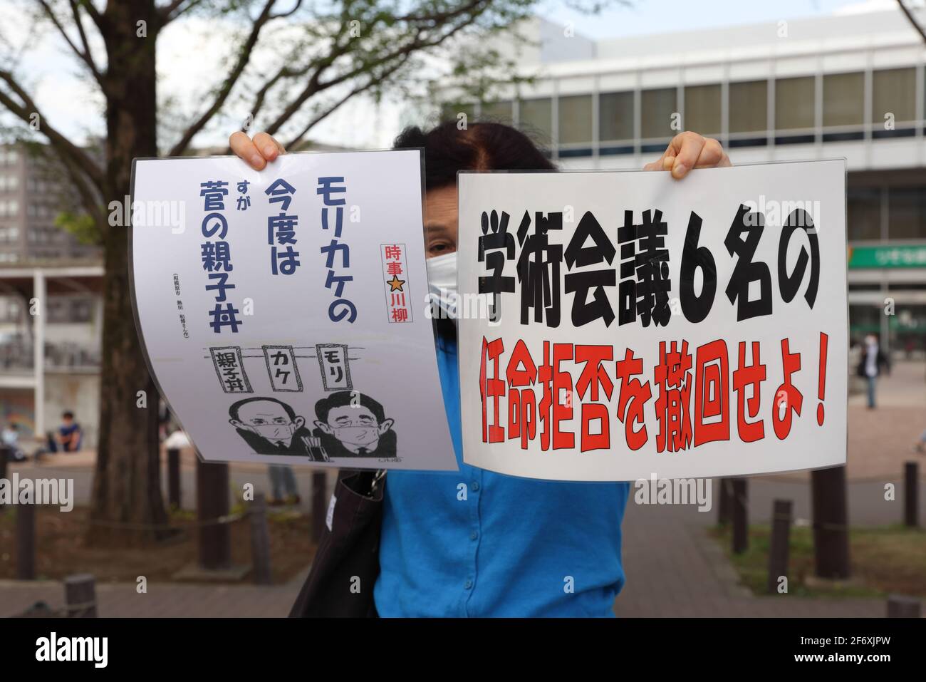 Eine maskierte Protesterin hält Plakate, die ihre Meinung während der Demonstration ausdrücken.Wir brauchen keine Waffen, aber Corona setzt Gegenmaßnahmen ein." Senioren zeigen ihre Meinung zu verschiedenen innenpolitischen Themen. Sie fordern unter anderem die Absage der Olympischen Spiele 2020 in Tokio, da sie die Verbreitung des Corona-Virus in Japan befürchtet. Stockfoto