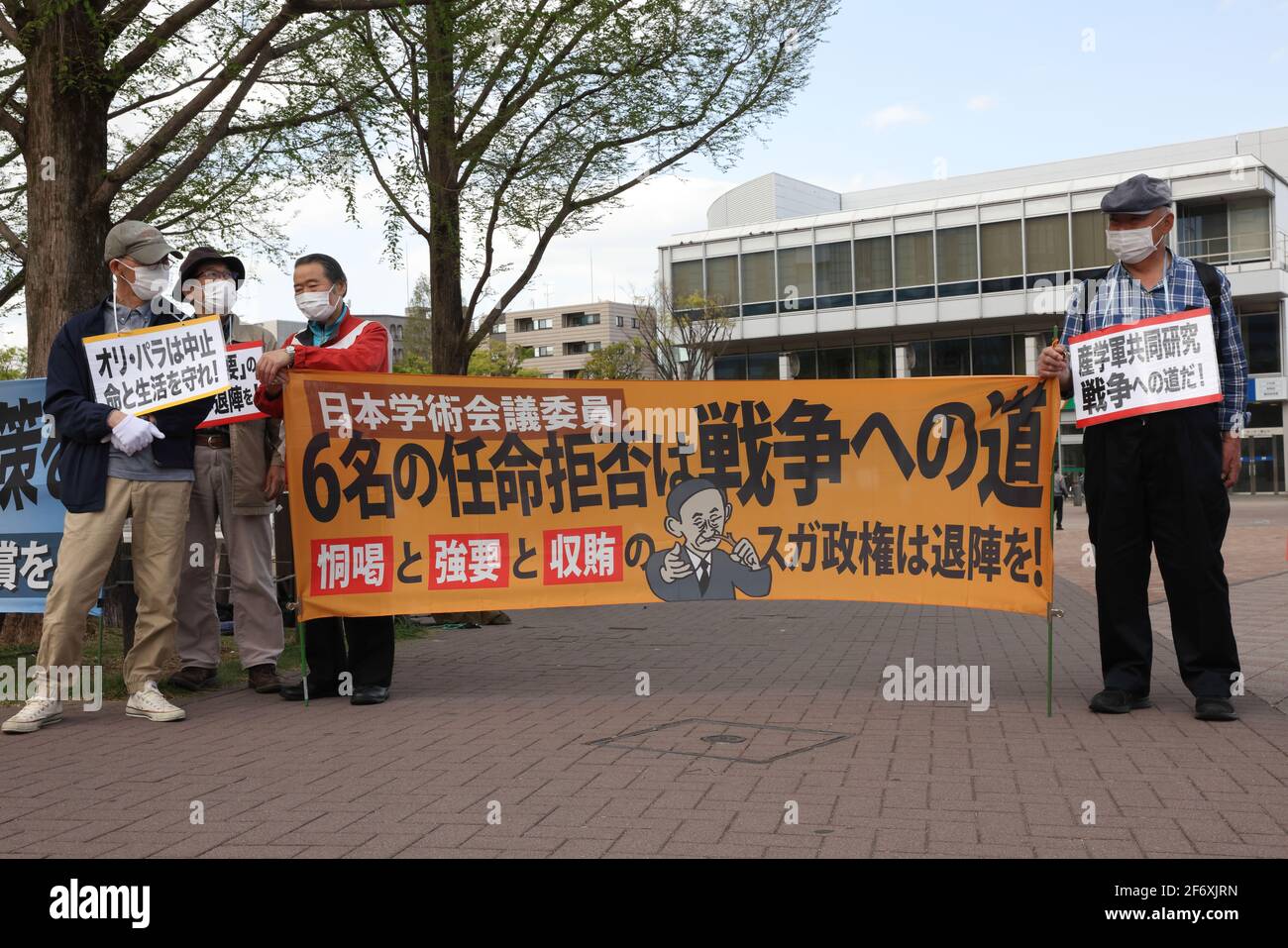 Maskierte Demonstranten halten Plakate und ein Banner, das ihre Meinung während der Demonstration zum Ausdruck bringt.Wir brauchen keine Waffen, sondern Corona Gegenmaßnahmen." Senioren zeigen ihre Meinung zu verschiedenen innenpolitischen Themen. Sie fordern unter anderem die Absage der Olympischen Spiele 2020 in Tokio, da sie die Verbreitung des Corona-Virus in Japan befürchtet. Stockfoto