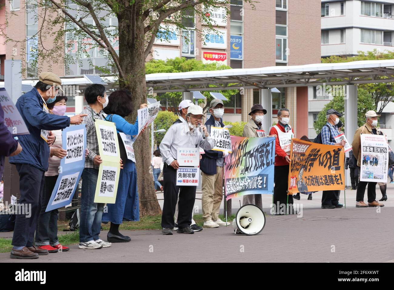 Yokohama, Japan. April 2021. Die maskierten Demonstranten halten Plakate, auf denen ihre Meinung während der Demonstration zum Ausdruck kommt.Wir brauchen keine Waffen, aber Corona Gegenmaßnahmen." Senioren zeigen ihre Meinung zu verschiedenen innenpolitischen Themen. Sie fordern unter anderem die Absage der Olympischen Spiele 2020 in Tokio, da sie die Verbreitung des Corona-Virus in Japan befürchtet. (Foto: Stanislav Kogiku/SOPA Images/Sipa USA) Quelle: SIPA USA/Alamy Live News Stockfoto