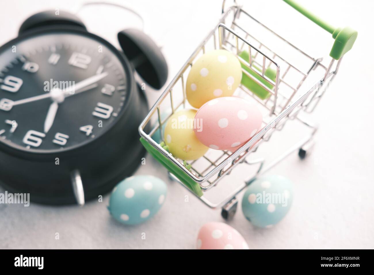 osterkonzept mit Ei im Warenkorb und Uhr auf Hintergrund. Stockfoto
