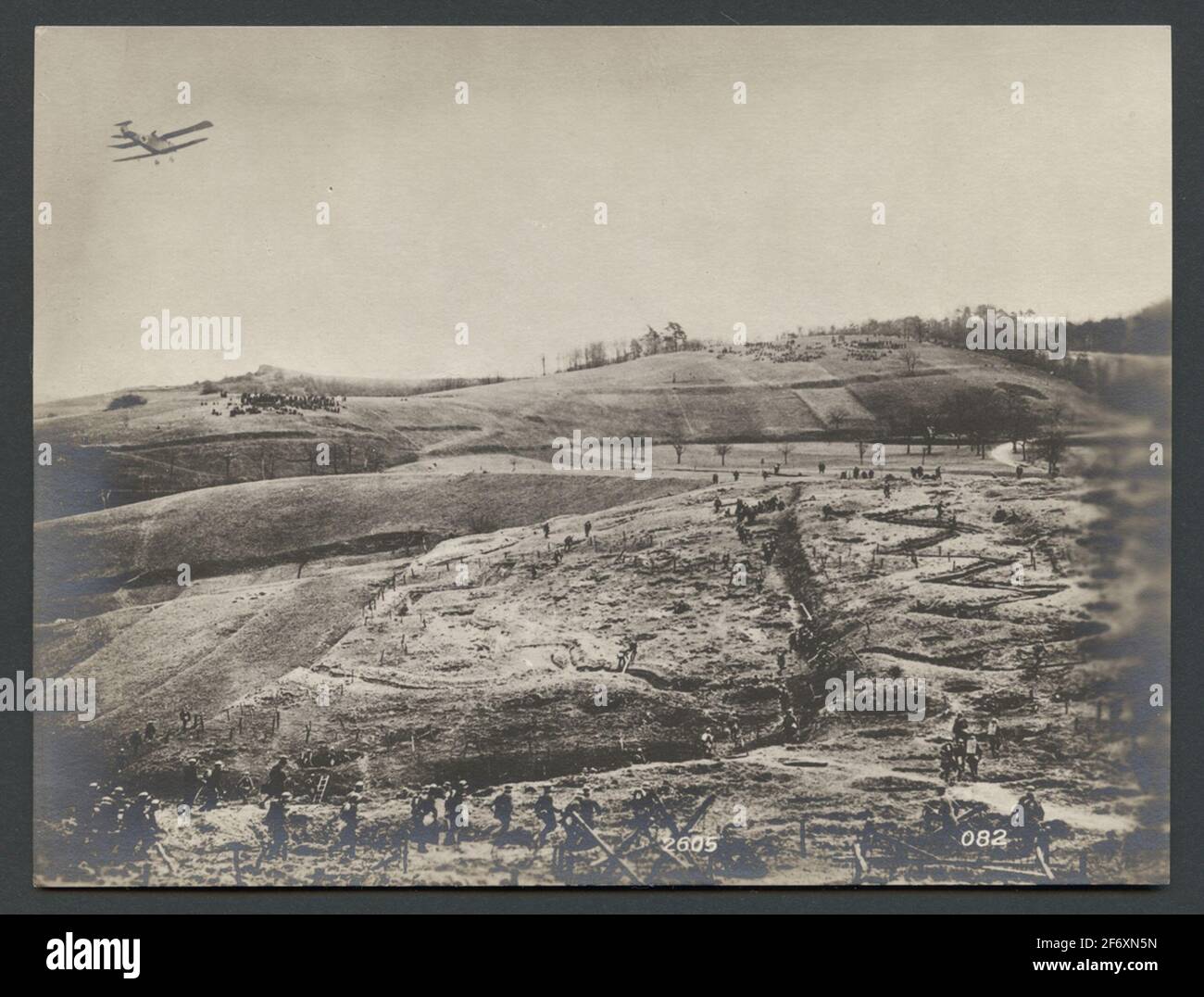 Das Bild zeigt eine hügelige Landschaft mit einem Hindernisparcours für die Ausbildung von Soldaten.über dem Feld passiert ein Flugzeug.Originaltext: 'Hinter der Deutschen Front befindet sich ein Übungsfeld, das mit allen Hindernissen, Granatlöchern, Regionen usw. eingerichtet ist, um den realen Bedingungen an der hauptlinia zu entsprechen. Das Bild zeigt die Zusammenarbeit der Infanterie mit einer sogenannten Infanterie, die mit Maschinengewehren und Bomben die feindlichen Schützencrews angreift. Das Bild zeigt eine hügelige Landschaft mit einem Hindernislauf für die Ausbildung von Soldaten.über dem Feld passiert ein Flugzeug.Originaltext: 'Hinter der Deutschen Front L Stockfoto