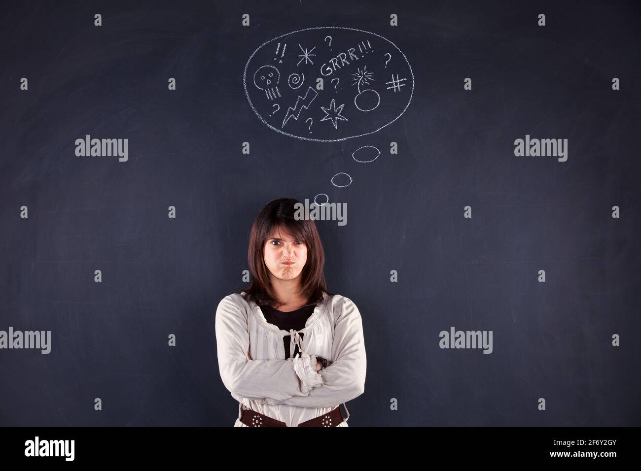Wütende Frau neben einer Tafel, die ihre Emotionen zeigt Stockfoto
