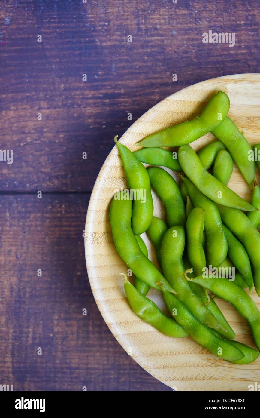 Eine Bambusplatte mit japanischen Edamame (Soja)-Bohnen auf einem rustikalen Holztisch. Stockfoto