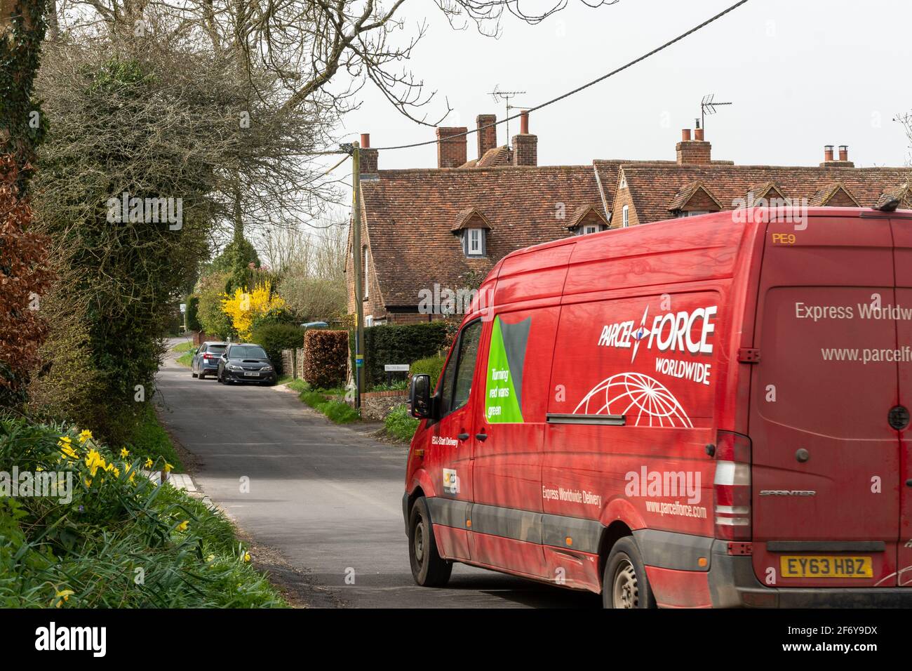 Der weltweite rote Lieferwagen von Parcelforce fährt durch das Dorf Dummer in Hampshire, England, Großbritannien Stockfoto