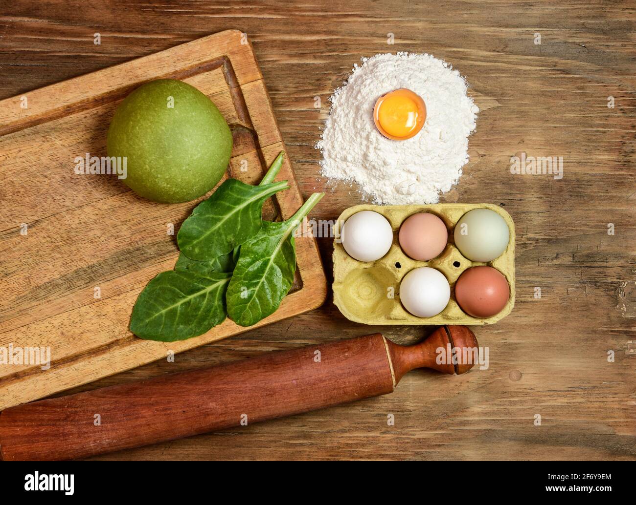 Grünes Teigbrötchen für die Herstellung von Nudeln, zubereitet auf dem Tisch mit Zutaten, traditionelle italienische Küche Stockfoto