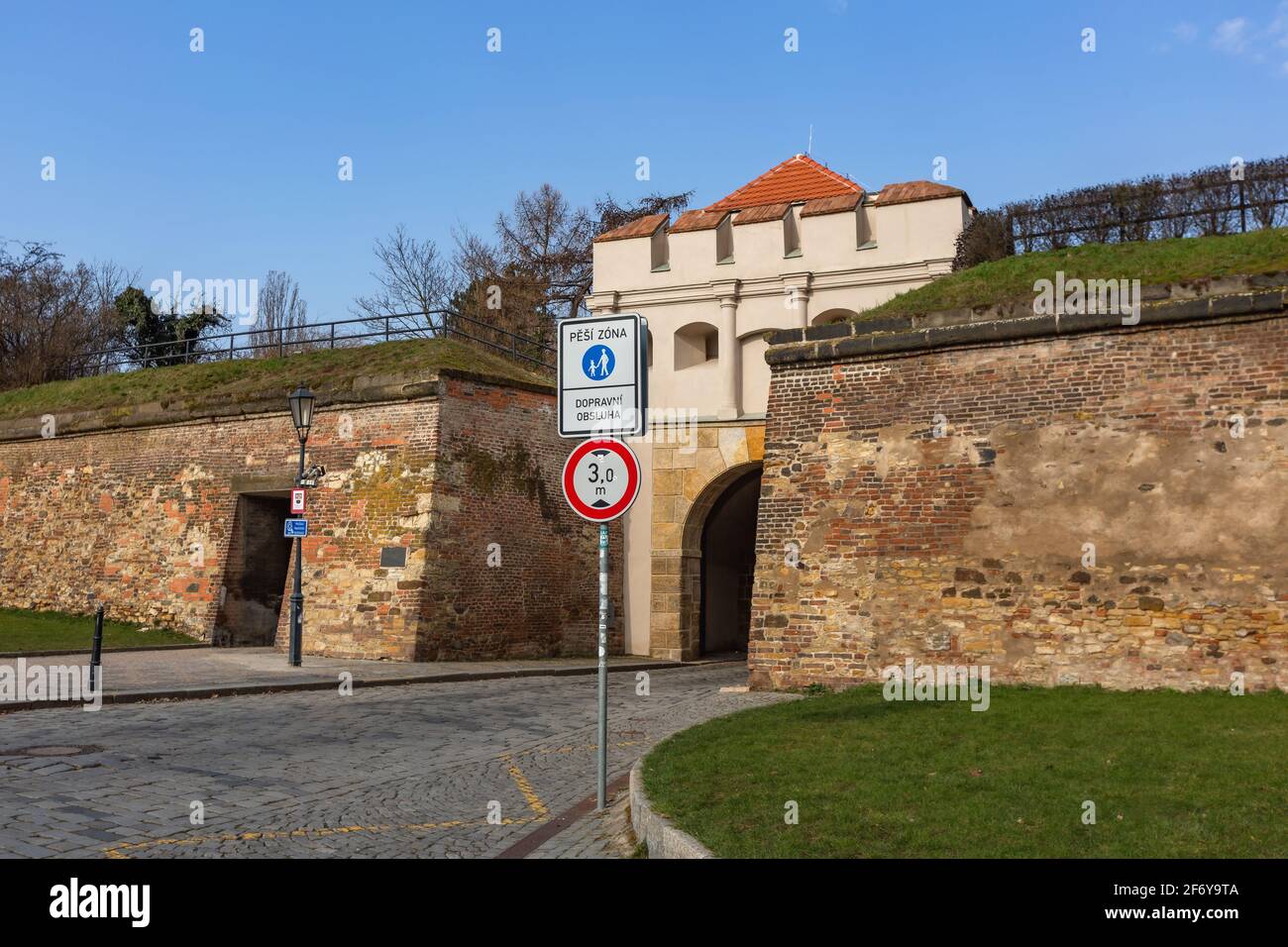 Prag, Tschechische Republik - März 26 2021: Blick auf das Tabor-Tor und eine Steinmauer, ein Teil der Festung, bei Vysehrad, Kopfsteinpflasterstraße, grüner Rasen Stockfoto