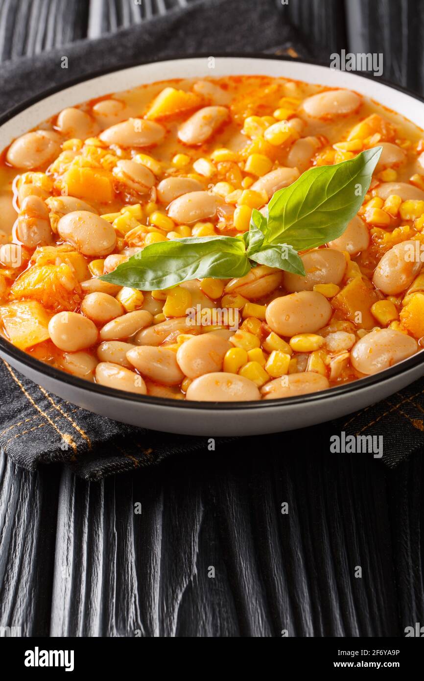 Bohnen mit Mais, Kürbis und Zwiebeln aus nächster Nähe in einer Schüssel auf dem Tisch eintoben. Vertikal Stockfoto