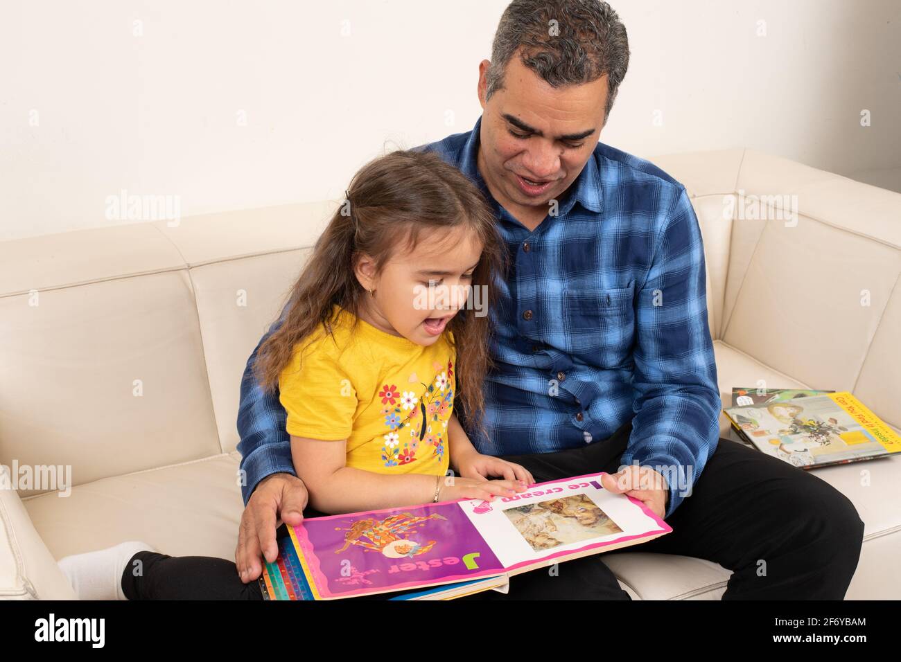 Vierjähriges Mädchen, das mit Großvater ein Bilderbuch ansieht Stockfoto