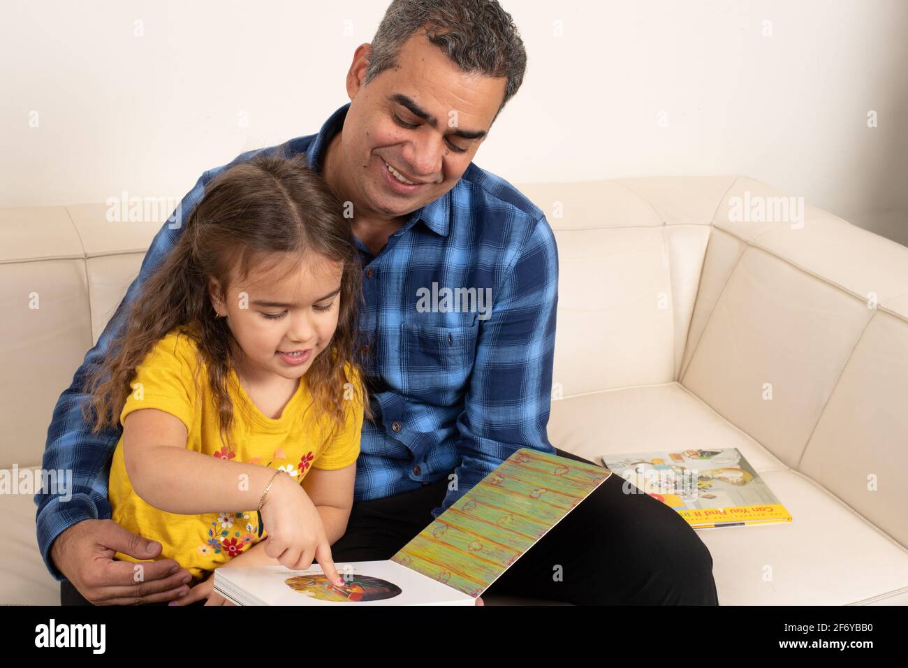 Vierjähriges Mädchen, das mit Großvater ein Bilderbuch ansieht Stockfoto