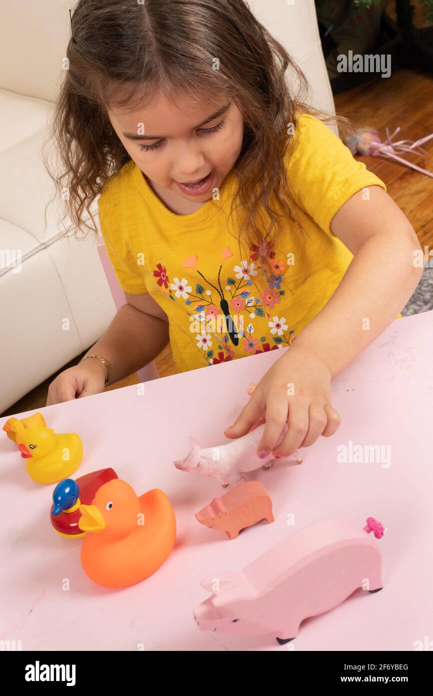Vier Jahre altes Mädchen, das mit Spielzeugtieren spielt, sie nach Größe und Typ verbindet und mit sich selbst spricht Stockfoto