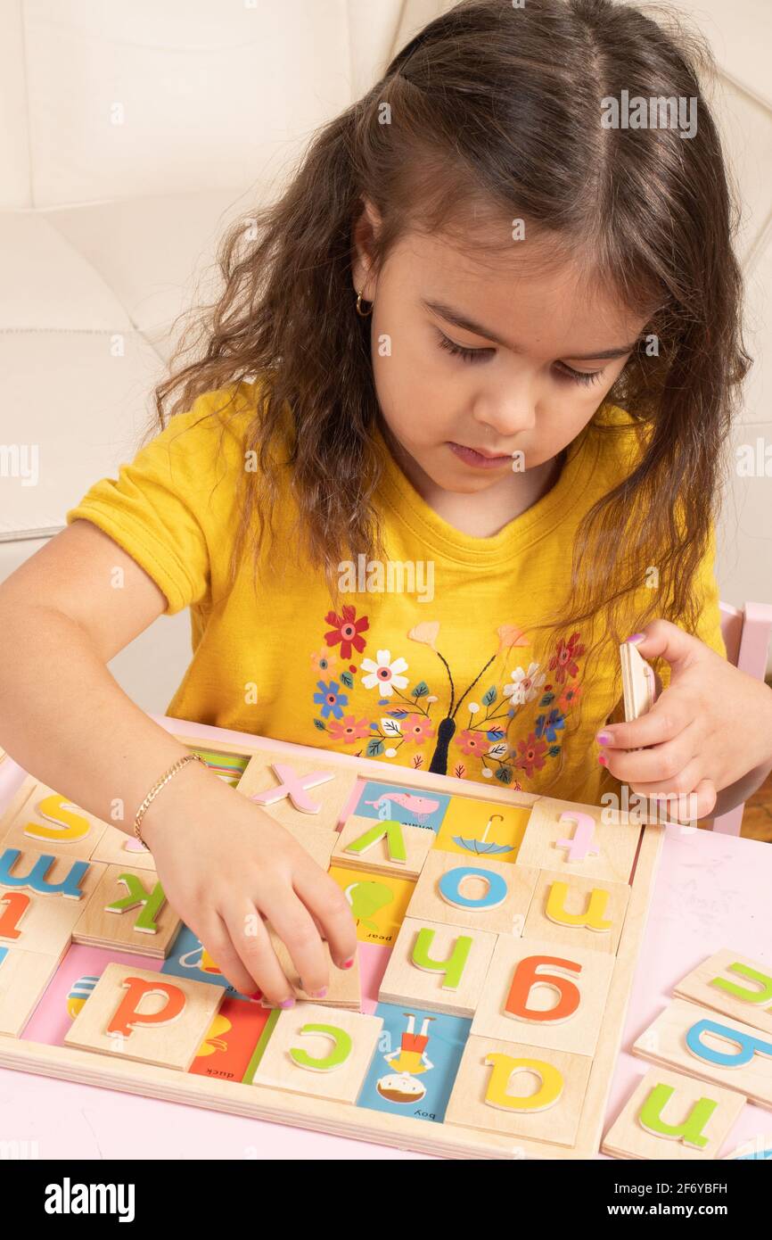 Vier Jahre altes Mädchen spielt mit Holz Alphabet Puzzle, setzen bunte Buchstaben in ihren Flecken Stockfoto