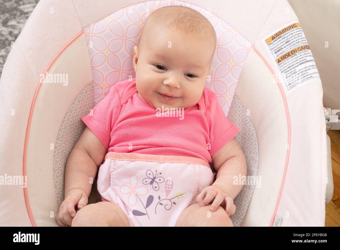 Nahaufnahme eines zwei Monate alten Mädchens, auf dem Kindersitz, lächelnd Stockfoto