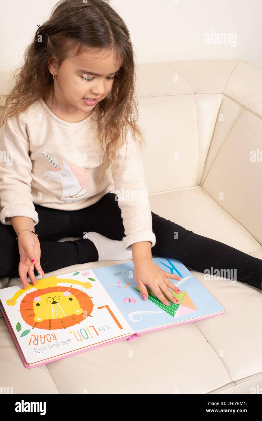 Vierjähriges Mädchen, das sich das Bilderbuch ansieht und spricht Stockfoto
