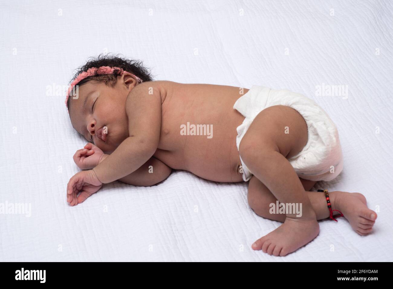 Neugeborenes Mädchen 3 Wochen alt, schläft auf der Seite, in voller Länge Stockfoto