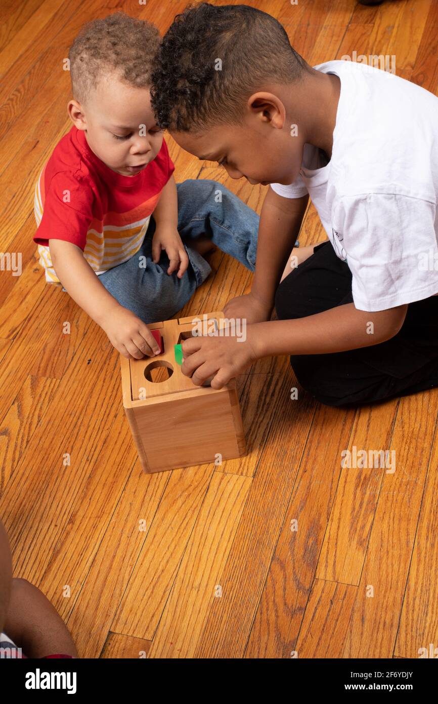 Brüder im Alter von 2 und 6 Jahren, die mit geometrischem Formsortierer spielen Stockfoto