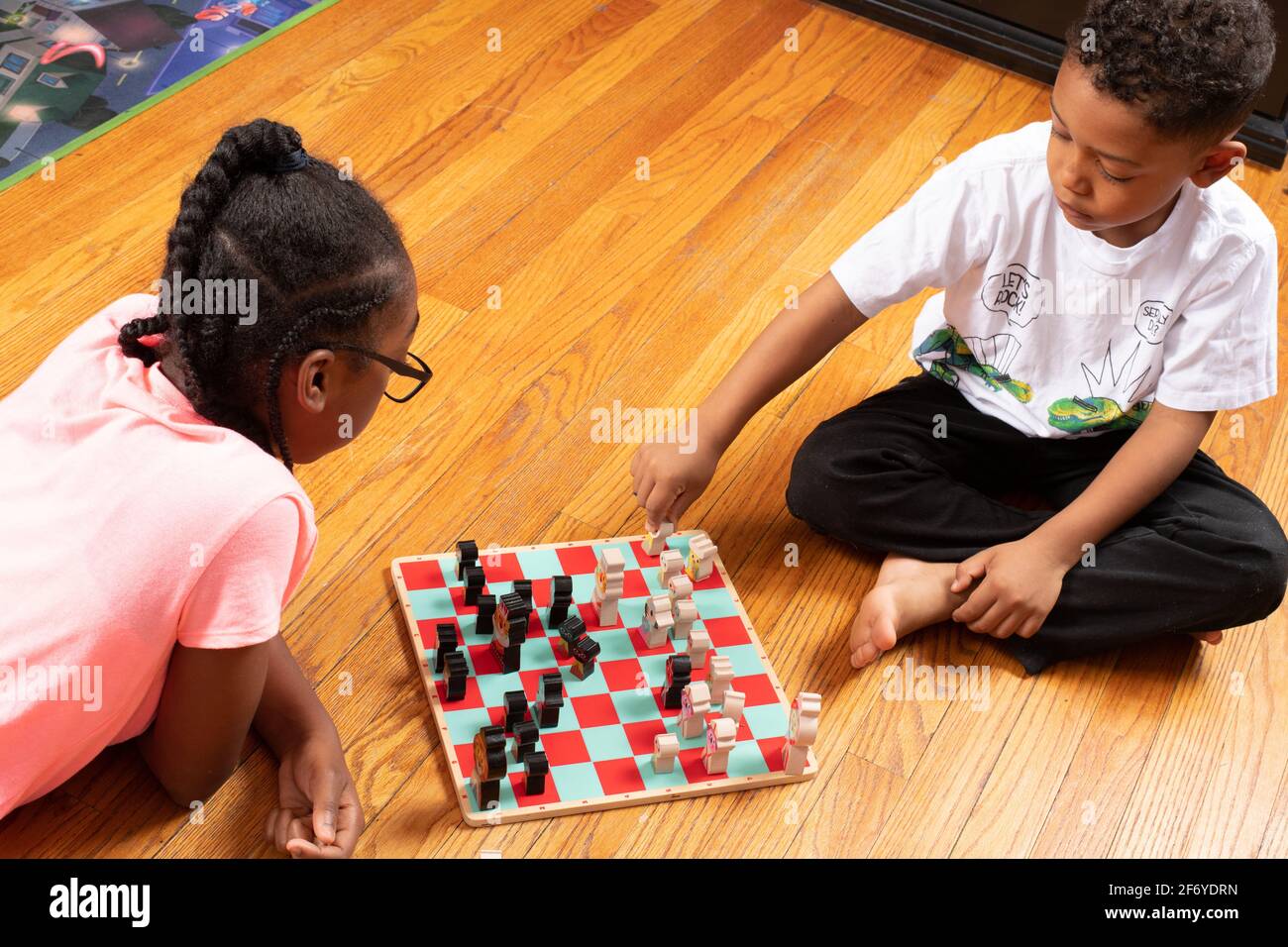 Das 11-jährige Mädchen spielt mit ihrem 6-jährigen Bruder Schach, spielt Spiel und lehrt ihn, wie man spielt Stockfoto