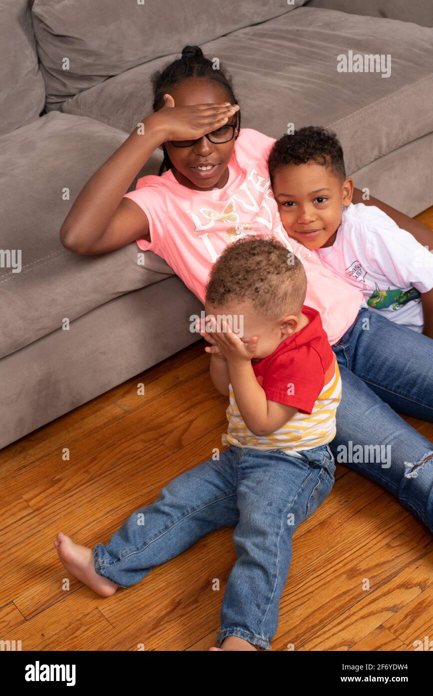 Geschwister im Alter von 11, 6 und 2 Jahren verstecken sich und suchen in Sichtweite, ein Kleinkind bedeckt seine Augen, so dass er denkt, er sei verschwunden Stockfoto