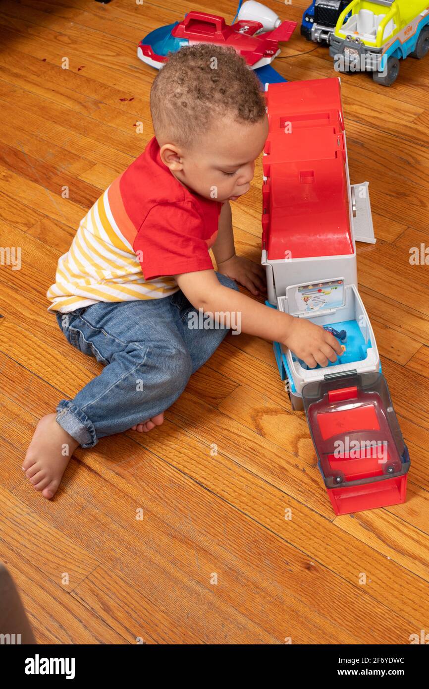 2-jähriger Junge, der mit Spielzeugfahrzeugen spielt Stockfoto