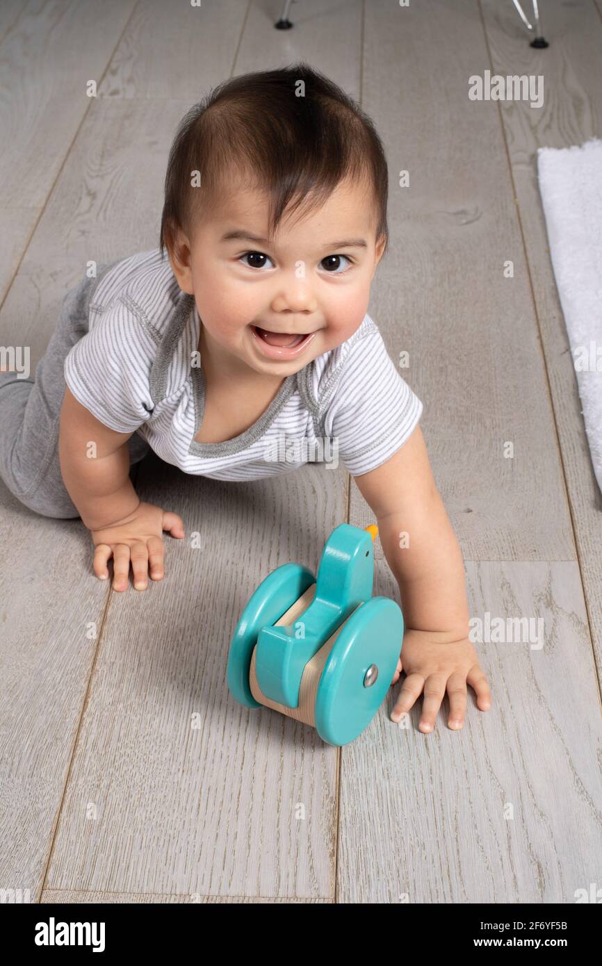 8 Monate altes Baby Junge Portrait nach dem Krabbeln in Richtung Spielzeug Stockfoto