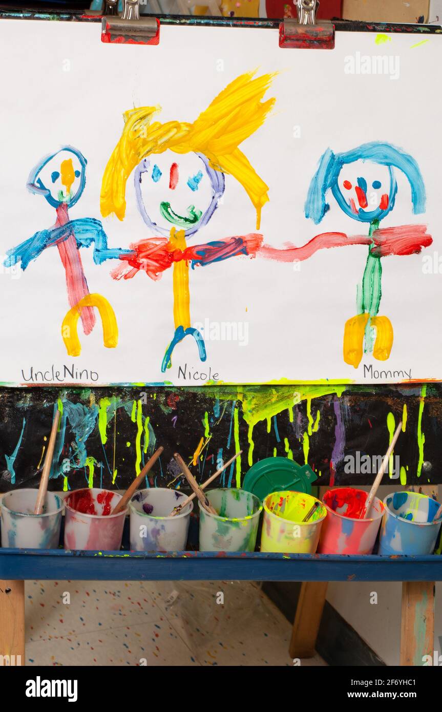 Vorschulklasse Klassenzimmer 3-4 Jahre alt Kind Gemälde auf Staffelei zeigt erkennbare menschliche Figuren Stockfoto