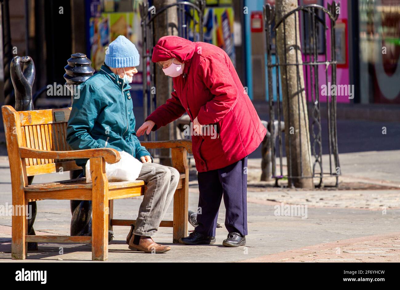 Dundee, Tayside, Schottland, Großbritannien. April 2021. UK Wetter: Frühlingssonne mit einer kühlen Brise durch Nordostschottland mit Temperaturen bis zu 12 Grad Die Menschen verbringen immer noch Zeit im Freien, um in Dundee City Kontakte zu knüpfen, da viele Geschäfte in der Tayside-Region während der Covid-19-Sperre auf Level 4 noch geschlossen sind. Ein älteres Paar ist sich der sozialen Distanzierungsrichtlinien und des Tragens von Gesichtsmasken bewusst, die draußen gemeinsam das sonnige Wetter im Stadtzentrum genießen. Kredit: Dundee Photographics/Alamy Live Nachrichten Stockfoto