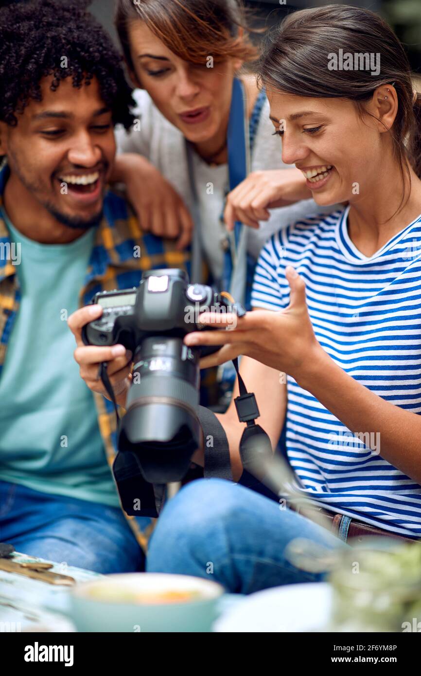 Freunde, die sich Kamerafotos im Garten der Bar ansehen. Gute Zeit der Freundschaft Stockfoto