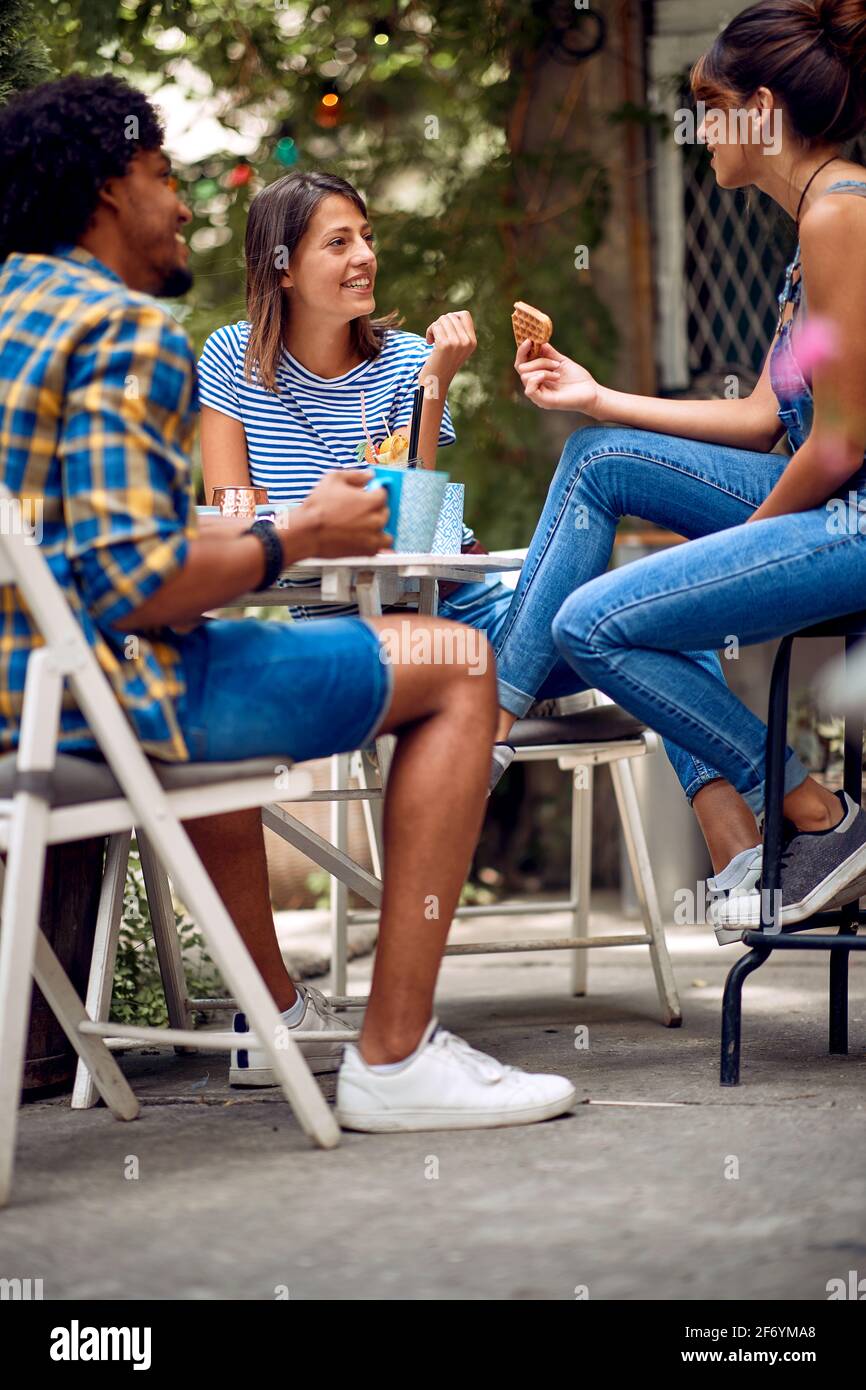 Fröhliche Freunde, die bei schönem Wetter im Hinterhof der Bar einen Snack zu sich nehmen. Gute Zeit der Freundschaft Stockfoto