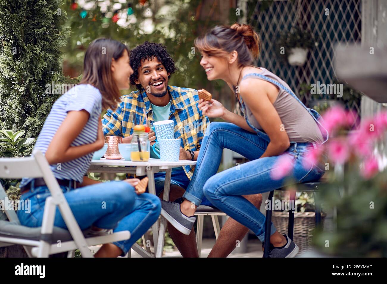 Fröhliche Freunde unterhalten sich bei schönem Wetter mit einem Snack und einem Drink im Hinterhof der Bar. Gute Zeit der Freundschaft Stockfoto