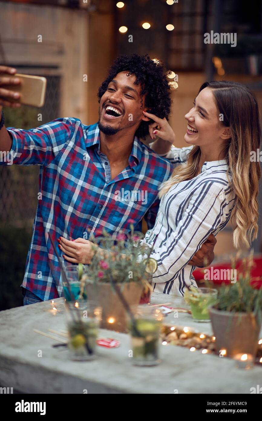 Glückliches Paar, das ein lustiges Selfie auf der Open-Air-Geburtstagsparty in einer schönen Sommerdämmerung macht. Gute Zeit der Freundschaft Stockfoto