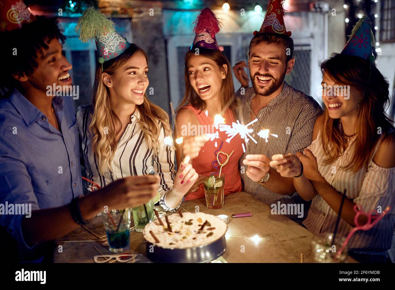 Eine Gruppe von Freunden genießt Sprinkler auf der Open-Air-Geburtstagsfeier an einem schönen Sommerabend. Gute Zeit der Freundschaft Stockfoto