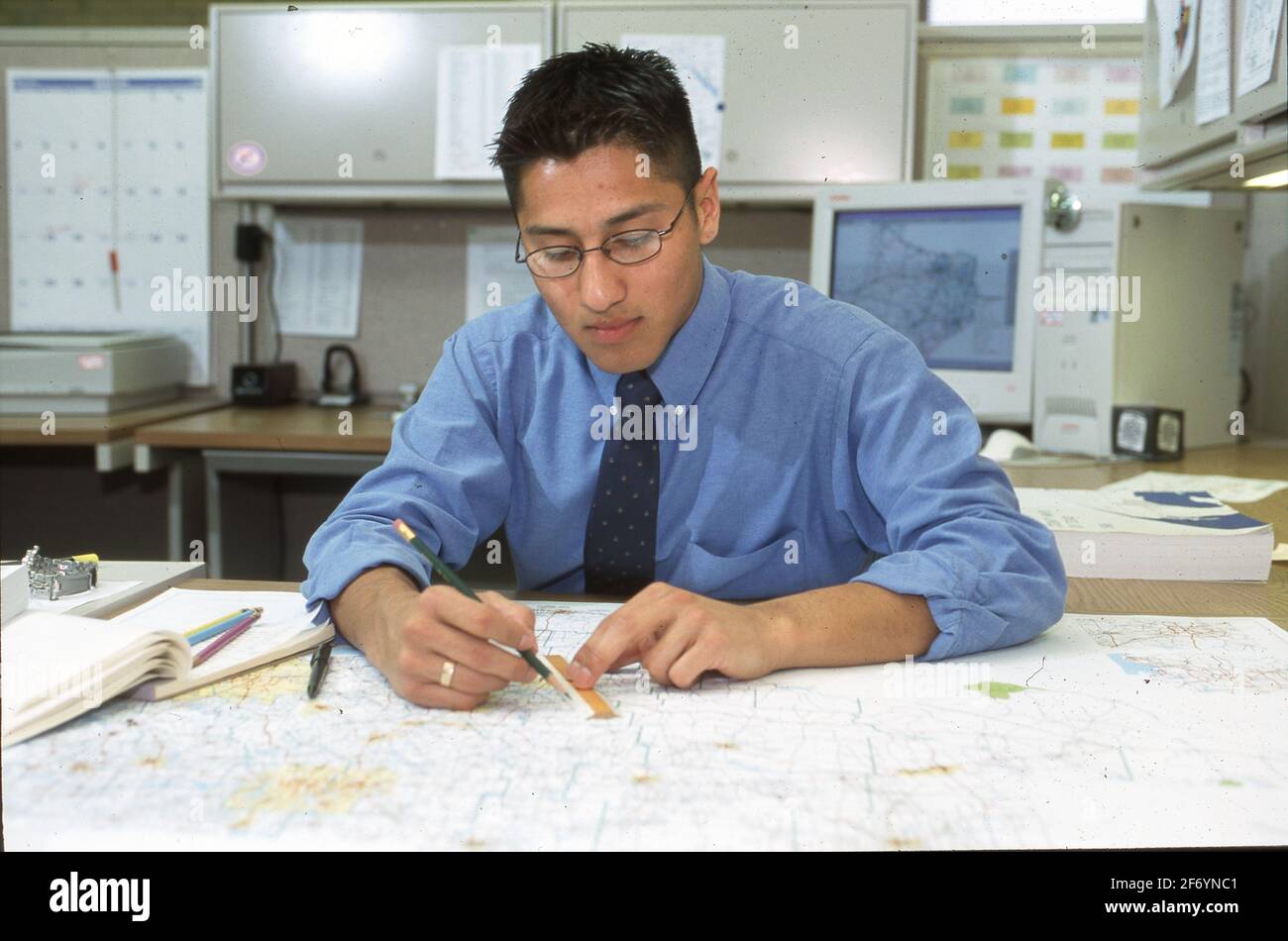 Austin, Texas, USA, 2002: Junger Hispanic-Mann, der bei seiner Arbeit als Planer am Texas Department of Transportation Karten verwendet. ©Bob Daemmrich Stockfoto