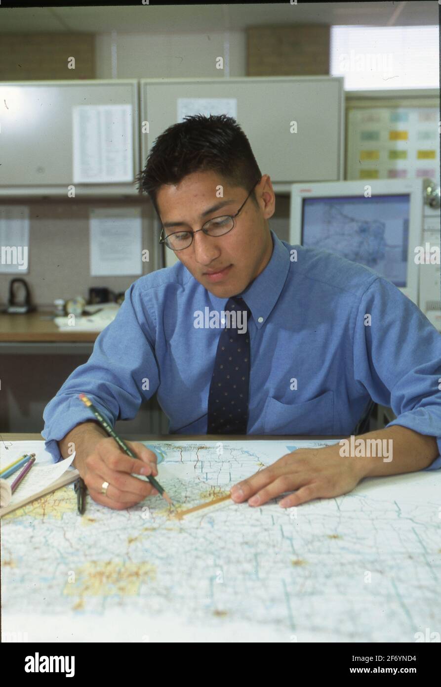 Austin, Texas, USA, 2002: Junger Hispanic-Mann, der bei seiner Arbeit als Planer am Texas Department of Transportation Karten verwendet. ©Bob Daemmrich Stockfoto