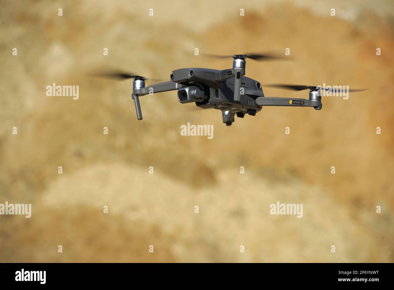 Multicopter-Drohne schwebt vor einer Sanddüne im Sonnenlicht Stockfoto